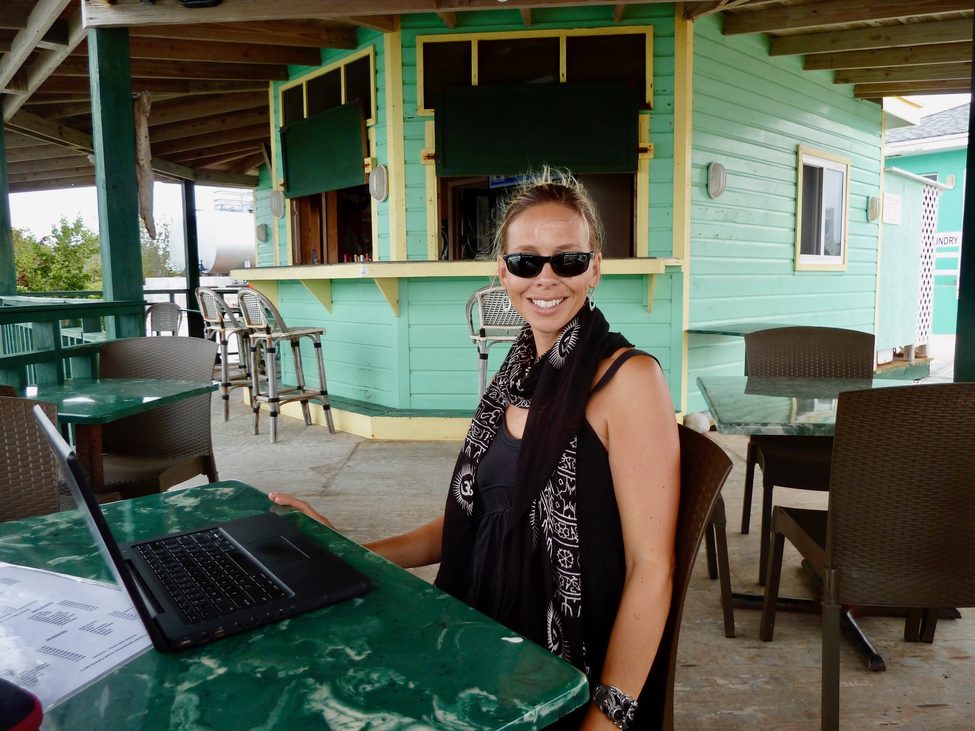 Julie working outdoors at a colorful island cafe with her laptop